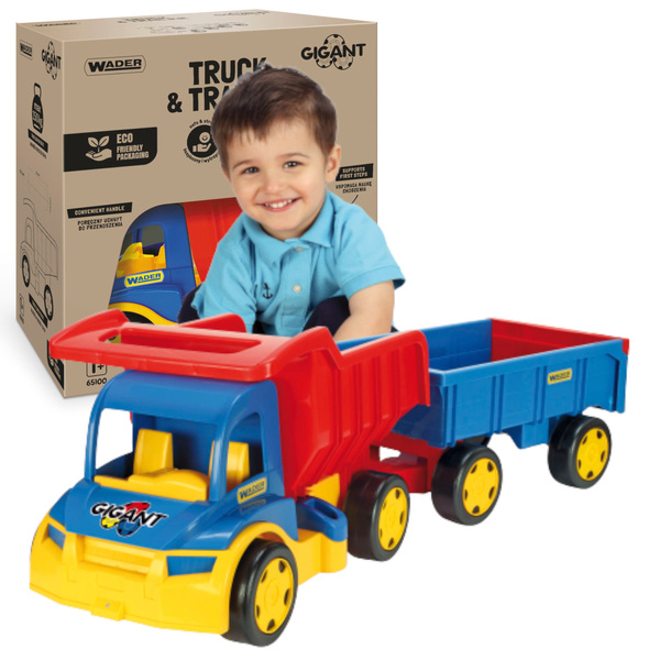 chłopiec bawi sie samochodem z przyczepą w kolorze niebiesko żółto czerwonych jest uśmiechniety i szczęśliwy